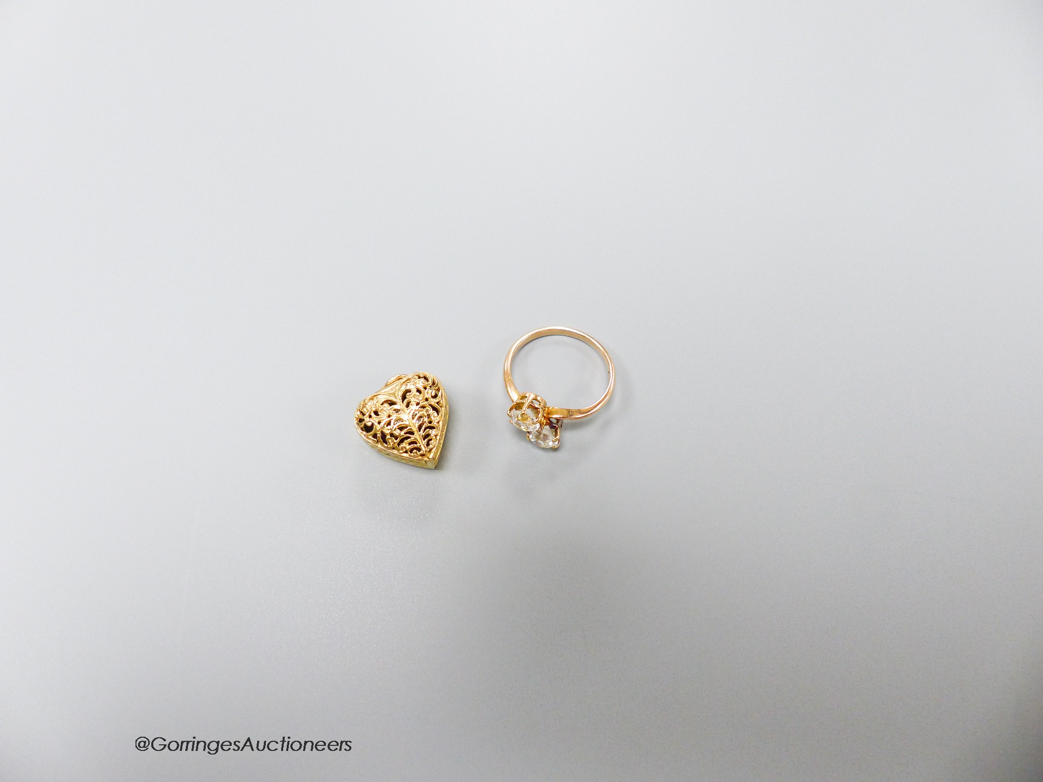 A modern 14k yellow metal and two white stone crossover ring, size L, gross 2.2 grams and a small pierced yellow metal heart shaped pendant, opening to reveal a two stone crossover ring, gross 5.2 grams.